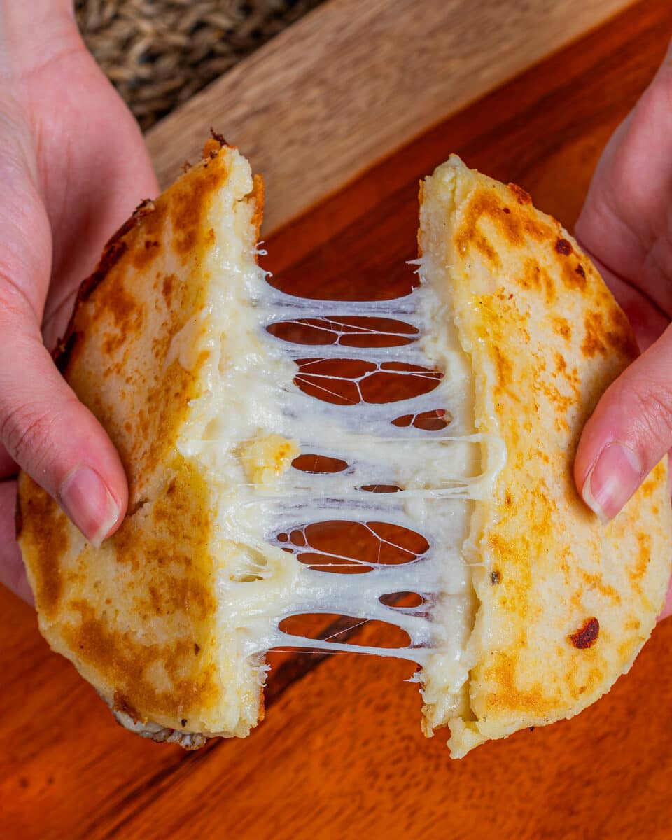 Arepa Xtra Queso dorada al comal, con el queso derretido estirándose